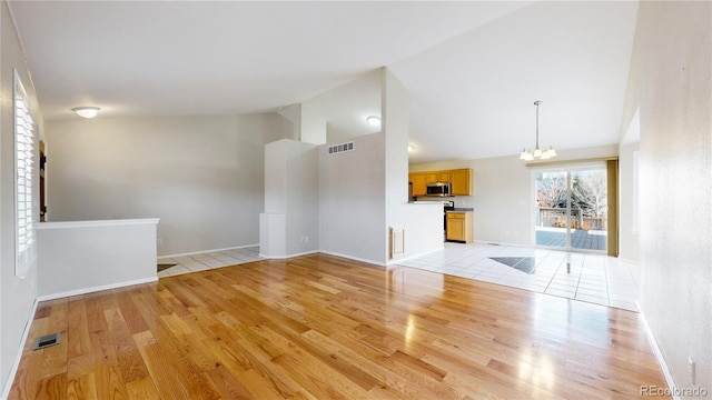 unfurnished living room featuring light hardwood / wood-style flooring, a chandelier, and lofted ceiling