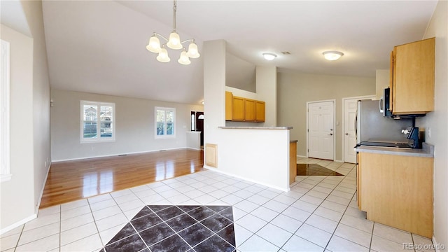 kitchen featuring vaulted ceiling, pendant lighting, light brown cabinets, an inviting chandelier, and light tile patterned flooring