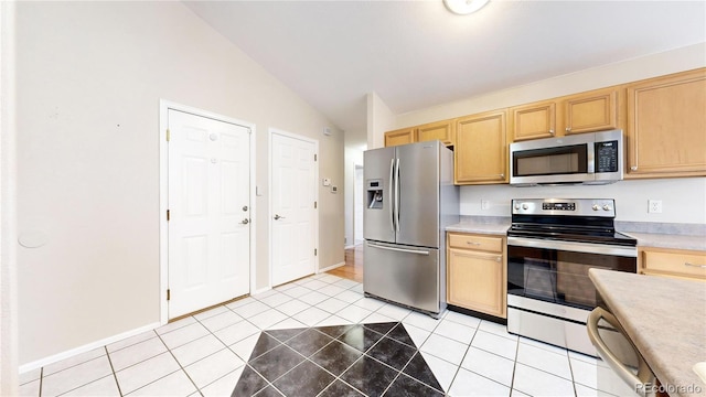 kitchen featuring light tile patterned floors, light brown cabinets, stainless steel appliances, and vaulted ceiling