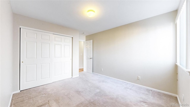 unfurnished bedroom with a closet and light colored carpet