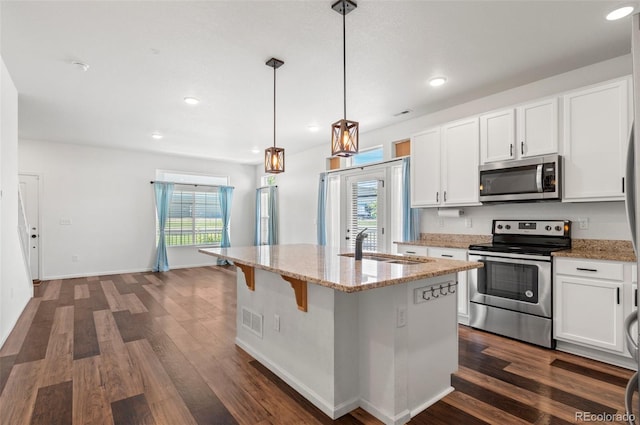 kitchen with white cabinets, decorative light fixtures, appliances with stainless steel finishes, and a healthy amount of sunlight