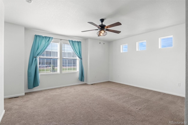 carpeted spare room featuring ceiling fan, a textured ceiling, and a healthy amount of sunlight