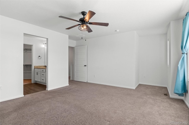 unfurnished bedroom featuring carpet floors, ensuite bathroom, ceiling fan, and a walk in closet