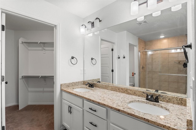 bathroom featuring a shower with door, vanity, and toilet