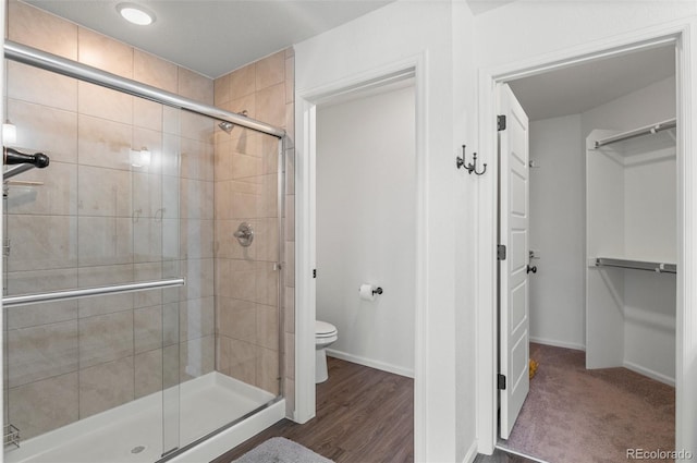 bathroom featuring wood-type flooring, an enclosed shower, and toilet