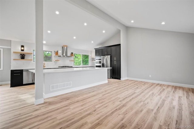 kitchen featuring wall chimney range hood, stainless steel appliances, vaulted ceiling with beams, kitchen peninsula, and light hardwood / wood-style flooring