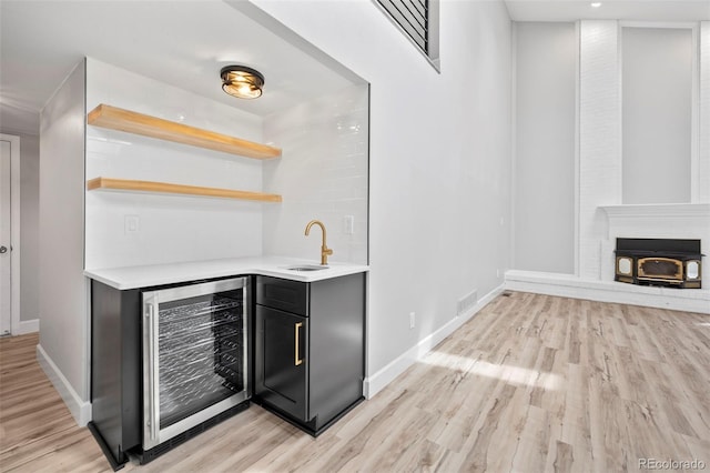 bar featuring sink, light hardwood / wood-style flooring, and wine cooler