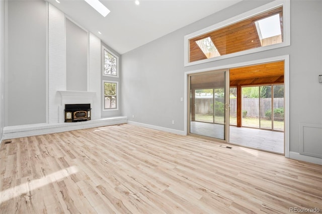 unfurnished living room with a skylight, a healthy amount of sunlight, and high vaulted ceiling