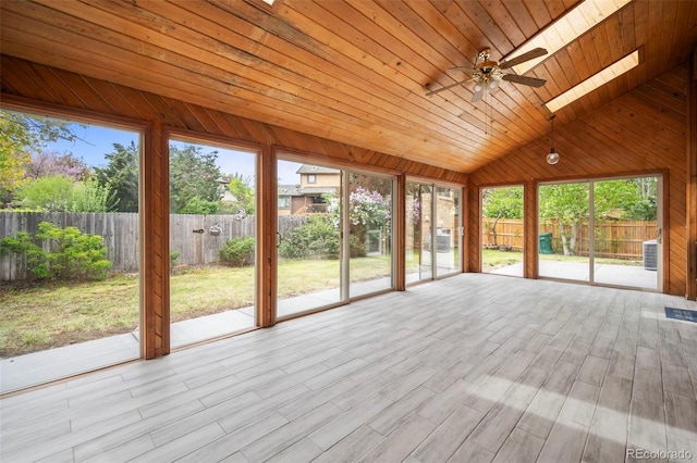 unfurnished sunroom featuring ceiling fan, wooden ceiling, vaulted ceiling with skylight, and a healthy amount of sunlight