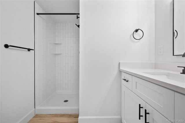 bathroom featuring vanity, wood-type flooring, and a tile shower