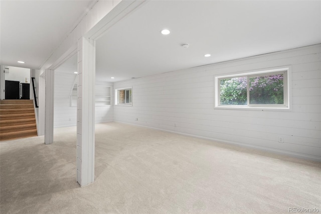 basement with light carpet and wood walls