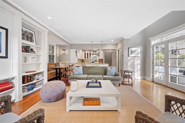 living room with crown molding, light hardwood / wood-style floors, and french doors