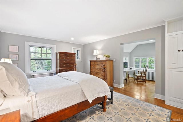 bedroom featuring ornamental molding, multiple windows, light hardwood / wood-style floors, and radiator