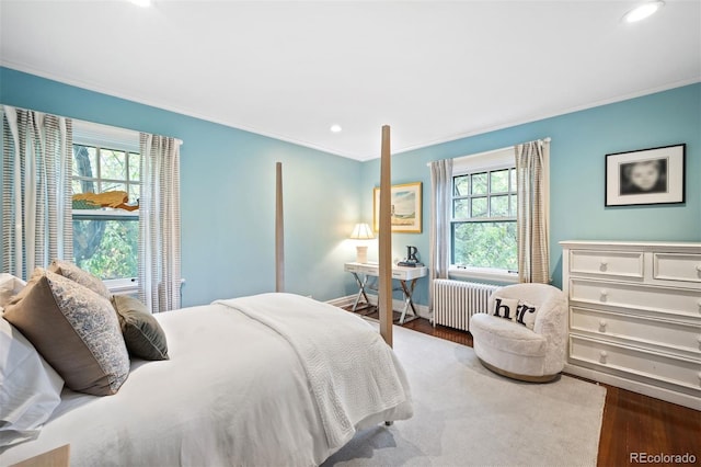 bedroom with ornamental molding, multiple windows, radiator heating unit, and hardwood / wood-style floors