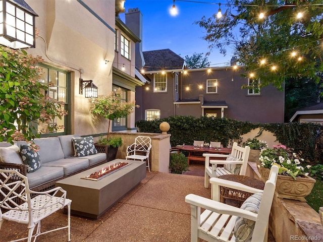 patio terrace at dusk with an outdoor living space with a fire pit