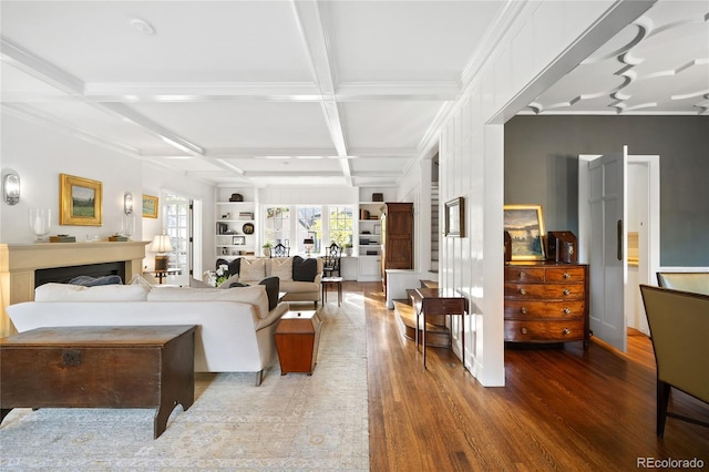 living room featuring wood-type flooring, beamed ceiling, built in shelves, crown molding, and coffered ceiling