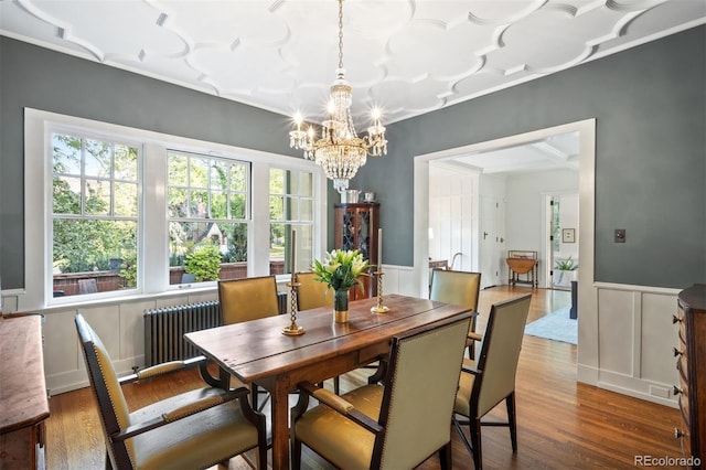 141 N Gilpin St, Denver, CO 80218 - dining area with radiator, a chandelier, wood finished floors, a wainscoted wall, and a decorative wall