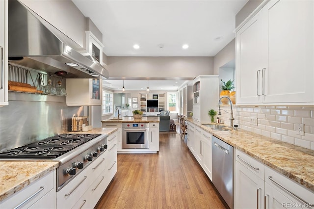 141 N Gilpin St, Denver, CO 80218 - kitchen featuring stainless steel appliances, wall chimney exhaust hood, open floor plan, light wood-style flooring, and white cabinets