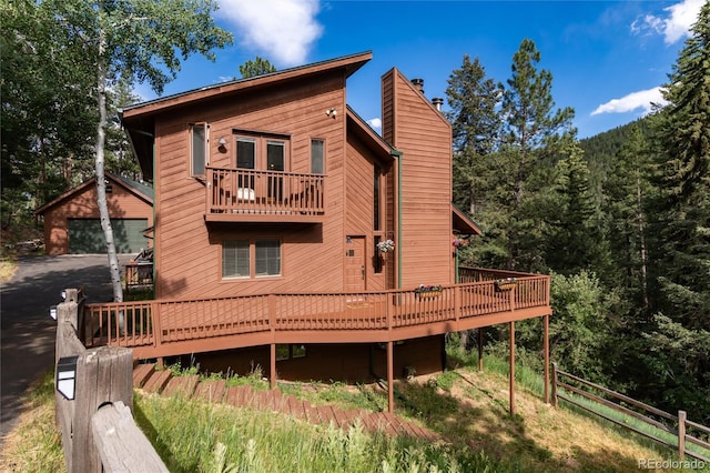 31673 Ponderosa Way, Evergreen, CO 80439 - rear view of property with a chimney, a deck, a wooded view, an outbuilding, and a garage