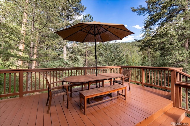 31673 Ponderosa Way, Evergreen, CO 80439 - wooden deck with outdoor dining space and a wooded view