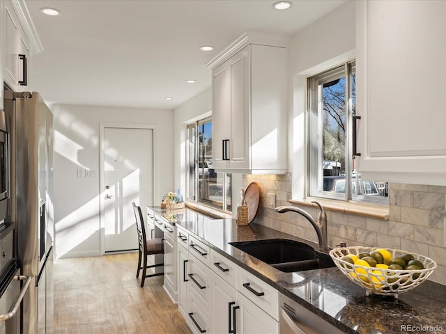 kitchen featuring dark stone countertops, plenty of natural light, white cabinets, and sink