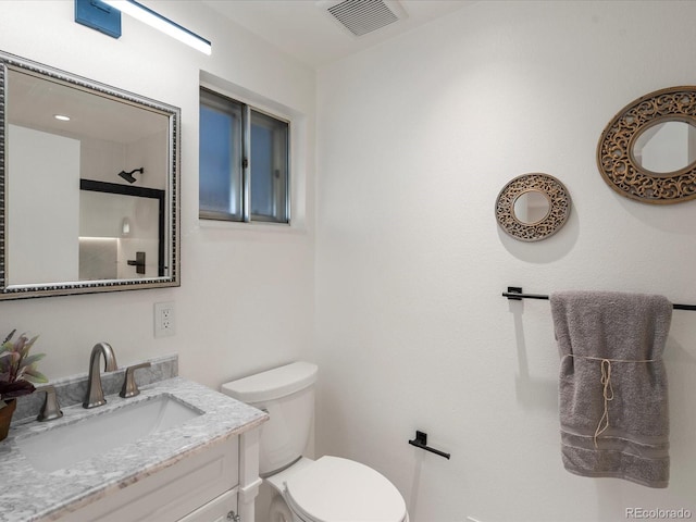 bathroom with a shower with door, vanity, and toilet