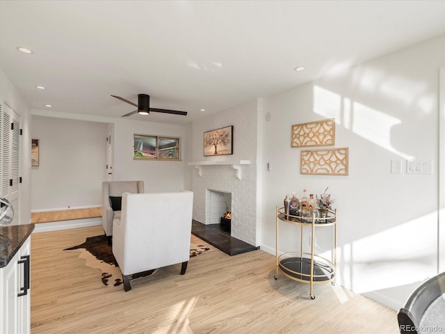 dining area featuring a fireplace, light hardwood / wood-style flooring, and ceiling fan