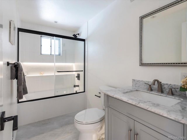 full bathroom featuring toilet, combined bath / shower with glass door, and vanity