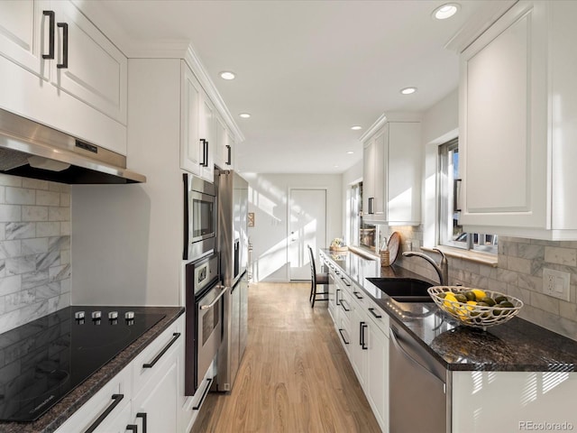 kitchen with decorative backsplash, light wood-type flooring, dark stone counters, stainless steel appliances, and white cabinets