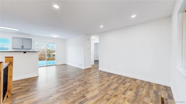 unfurnished living room with baseboards, wood finished floors, visible vents, and recessed lighting