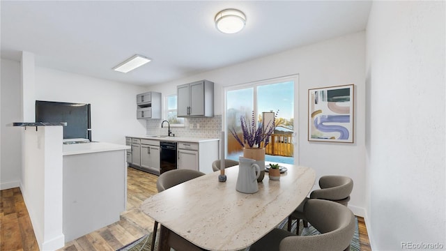 kitchen featuring gray cabinets, light countertops, a sink, and fridge