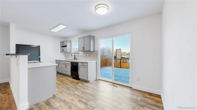 kitchen featuring light wood-style flooring, a sink, light countertops, fridge, and backsplash