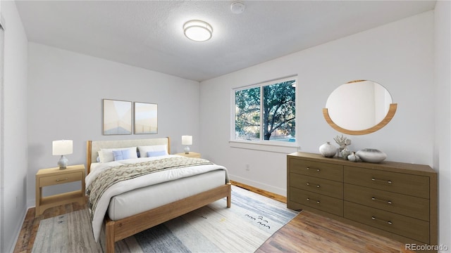 bedroom with light wood-style flooring, baseboards, and a textured ceiling