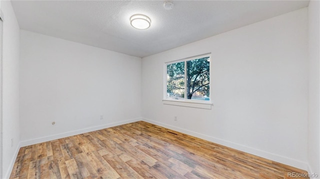 unfurnished room featuring a textured ceiling, light wood-style flooring, and baseboards