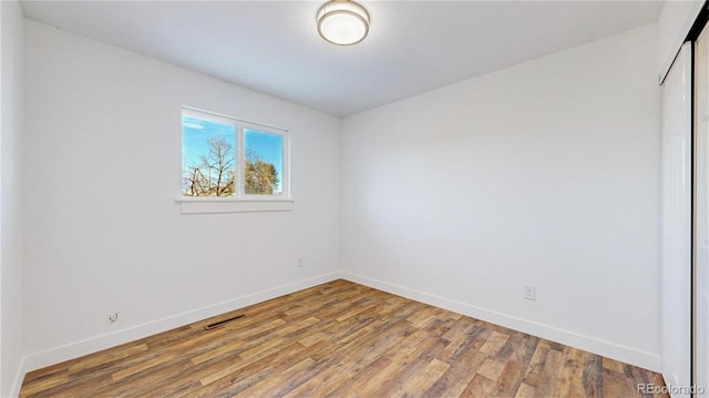 interior space with a closet, wood finished floors, visible vents, and baseboards