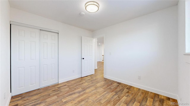 unfurnished bedroom with a closet, baseboards, and wood finished floors