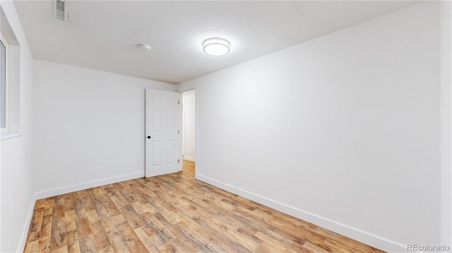 spare room featuring visible vents, light wood-style flooring, and baseboards