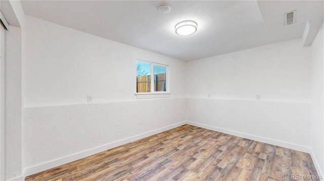 spare room featuring visible vents, baseboards, and wood finished floors