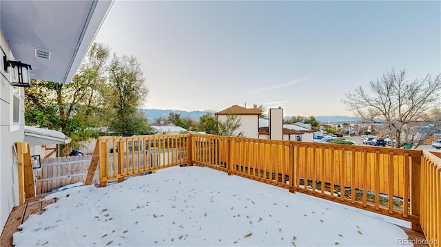 snow covered deck featuring fence and a mountain view