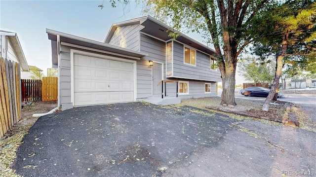 tri-level home featuring fence, driveway, and an attached garage