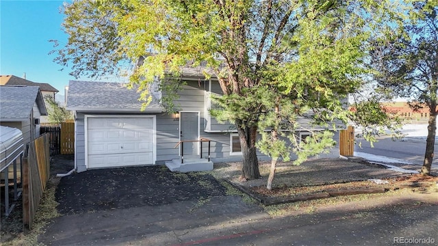 view of front of property with a shingled roof, an attached garage, and fence