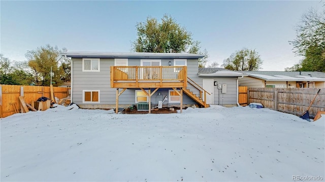 snow covered property featuring a fenced backyard, stairs, and a deck