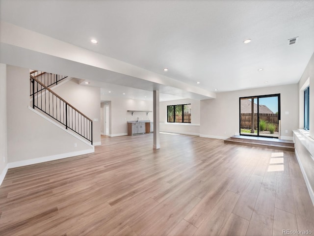 unfurnished living room featuring light hardwood / wood-style flooring, sink, and plenty of natural light