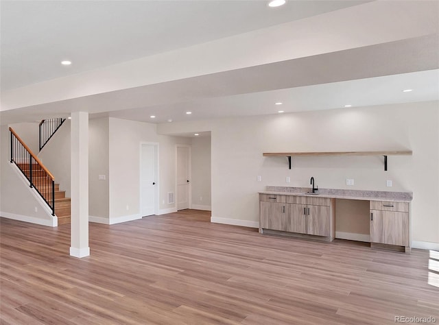 bar featuring sink, light hardwood / wood-style flooring, and light brown cabinets