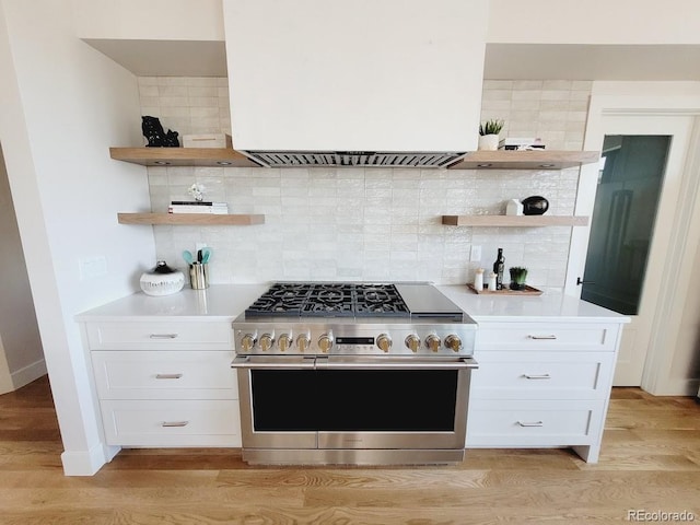 kitchen with white cabinetry, decorative backsplash, light hardwood / wood-style flooring, and range with two ovens