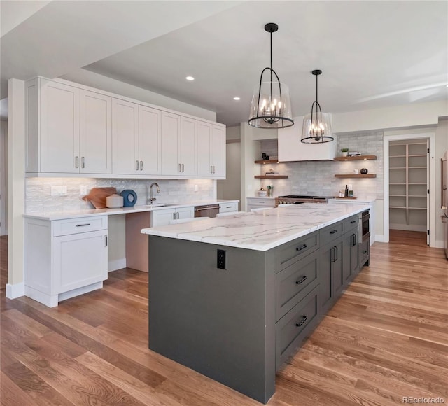 kitchen with white cabinetry, a center island, light hardwood / wood-style flooring, and a notable chandelier