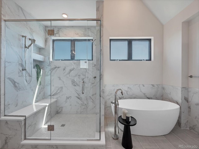 bathroom with lofted ceiling, independent shower and bath, and tile walls