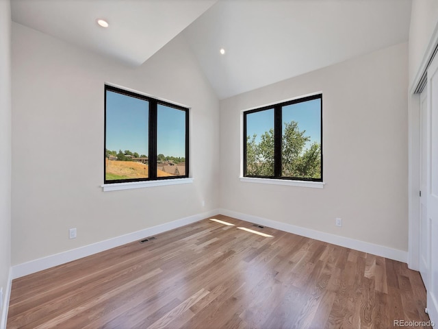 spare room featuring light hardwood / wood-style floors and vaulted ceiling