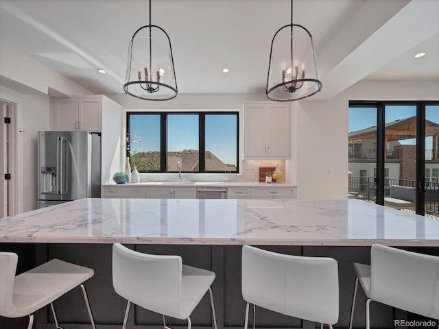 kitchen with white cabinetry, decorative light fixtures, stainless steel appliances, and an inviting chandelier