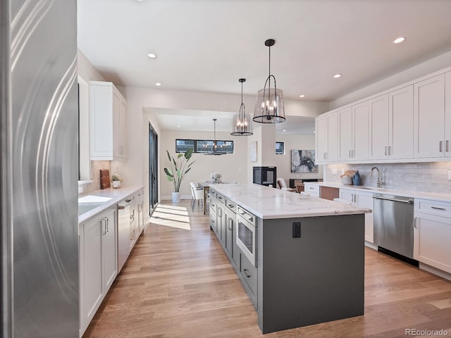 kitchen featuring decorative light fixtures, tasteful backsplash, white cabinets, a center island, and stainless steel appliances